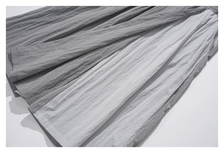 Gray garment fabric shown in overlapping folds, with a fine grid pattern and a lighter solid panel.
