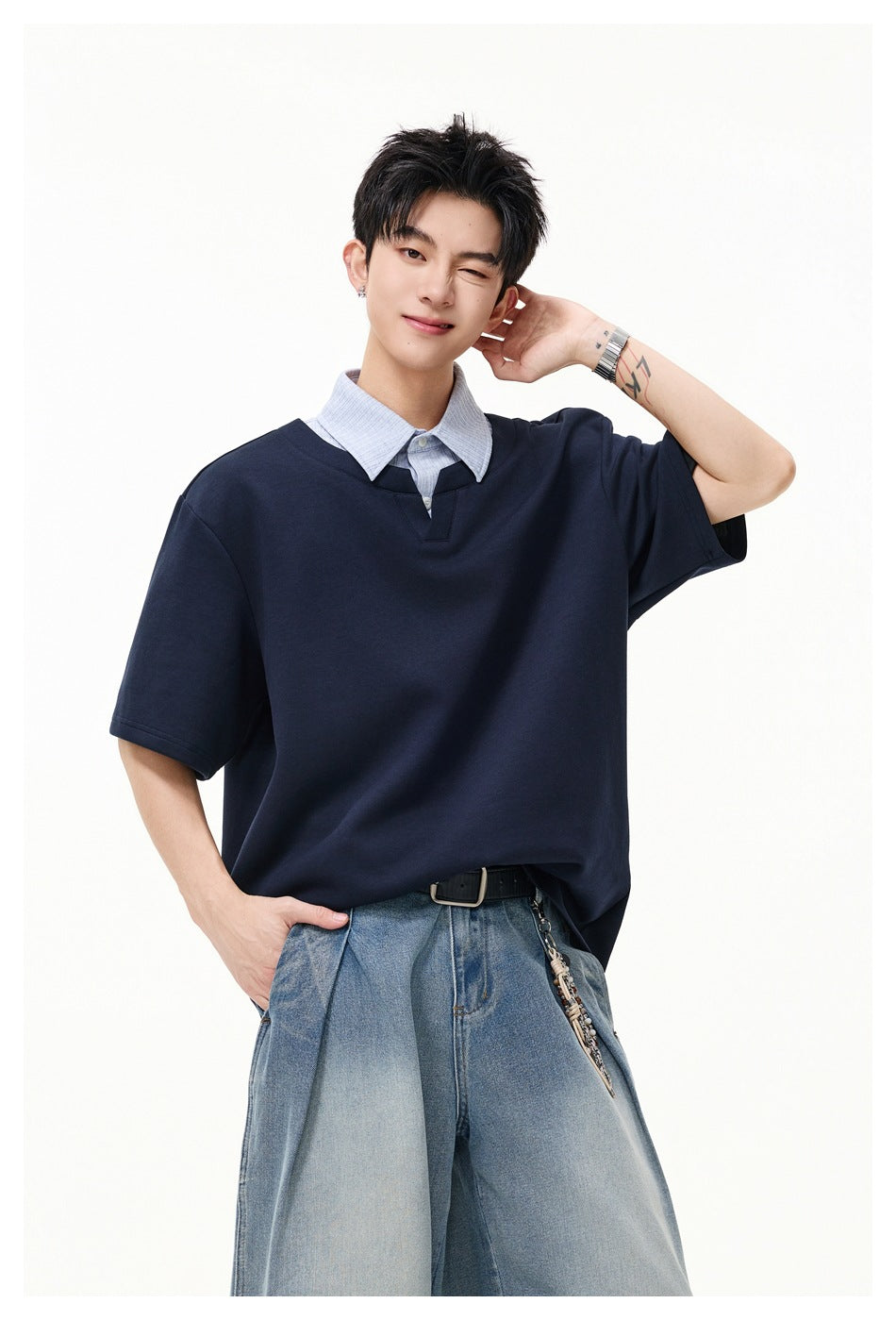 Model wearing a navy short-sleeve top with a pale striped collar and placket, paired with light-wash jeans.