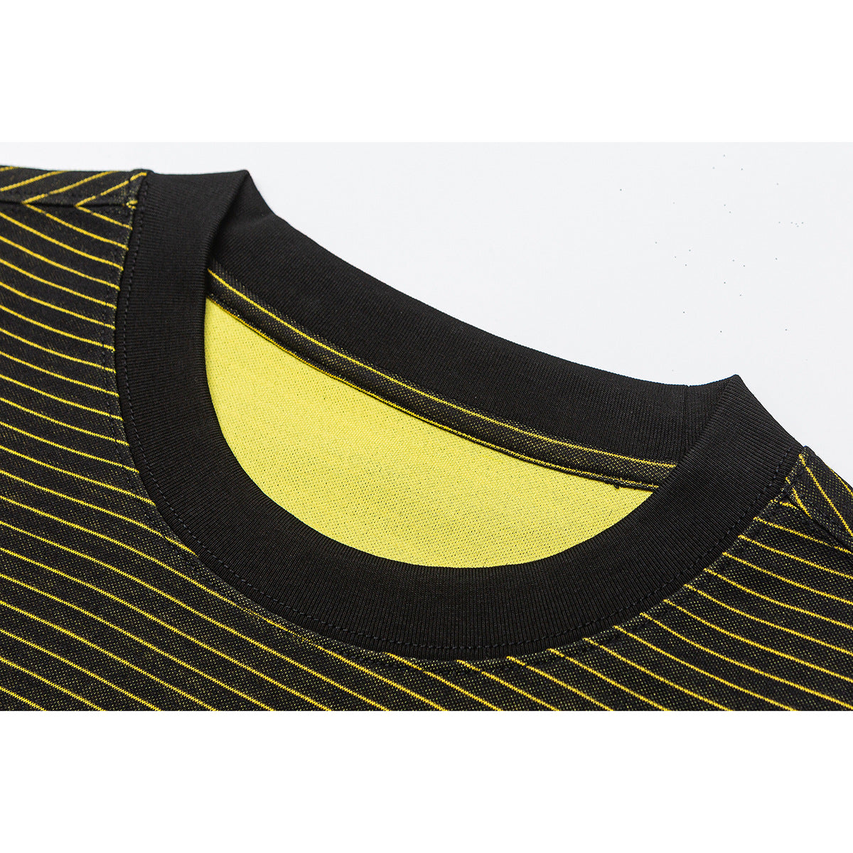 Close-up of a black ribbed crew neckline on a black shirt with thin yellow stripes and a yellow inner panel.