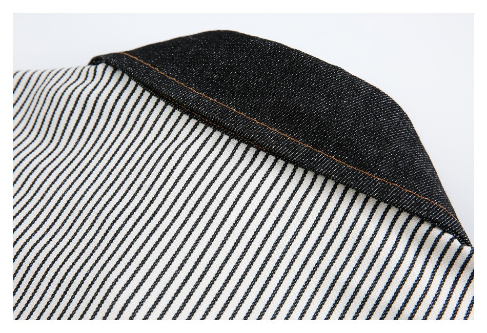Close-up of a black fabric panel with orange topstitching beside cream-and-black striped fabric.