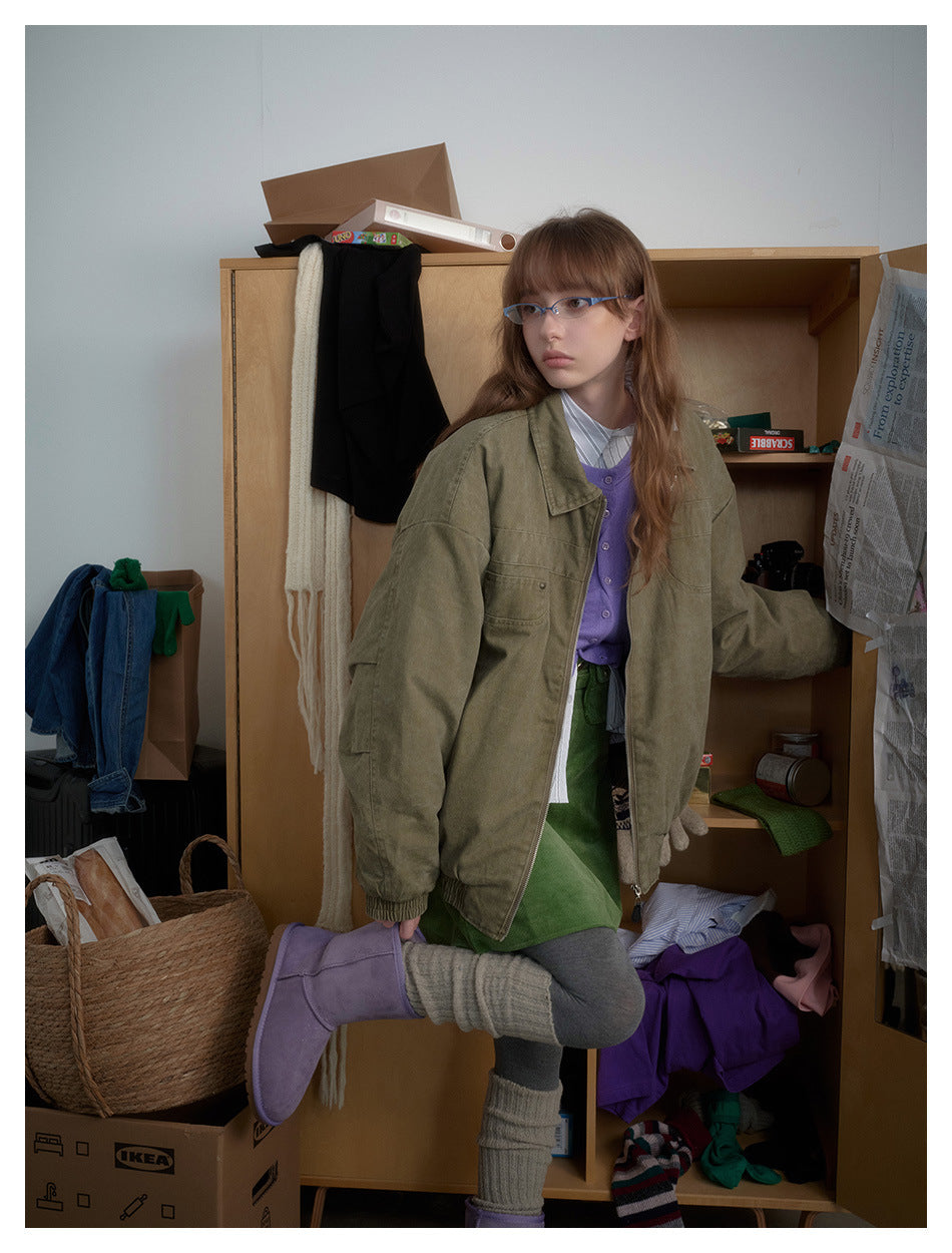 A model wears an oversized olive zip-front jacket with a wide collar, chest pockets and gathered cuffs.