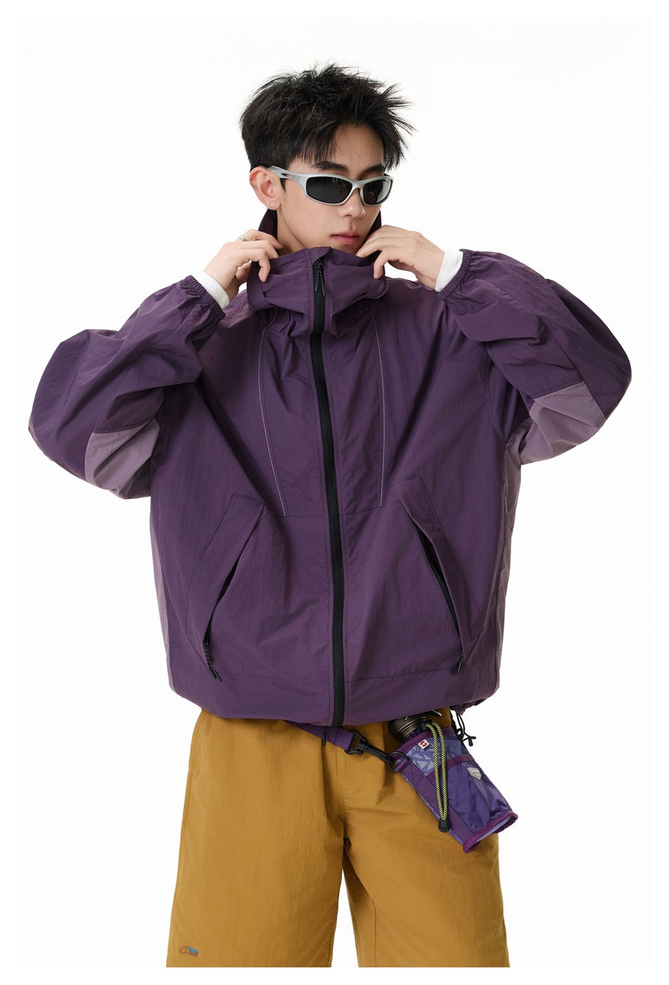Model adjusts the high collar of a plum jacket, showing its front zipper and angled pockets.