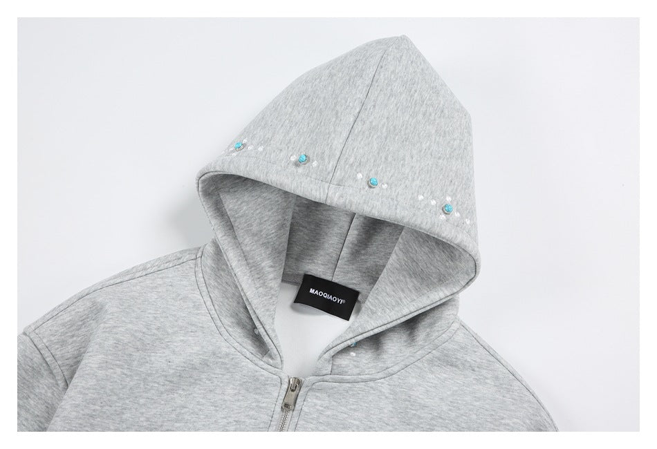 Close-up of a light gray hoodie hood with turquoise and white embellishments along its edge.
