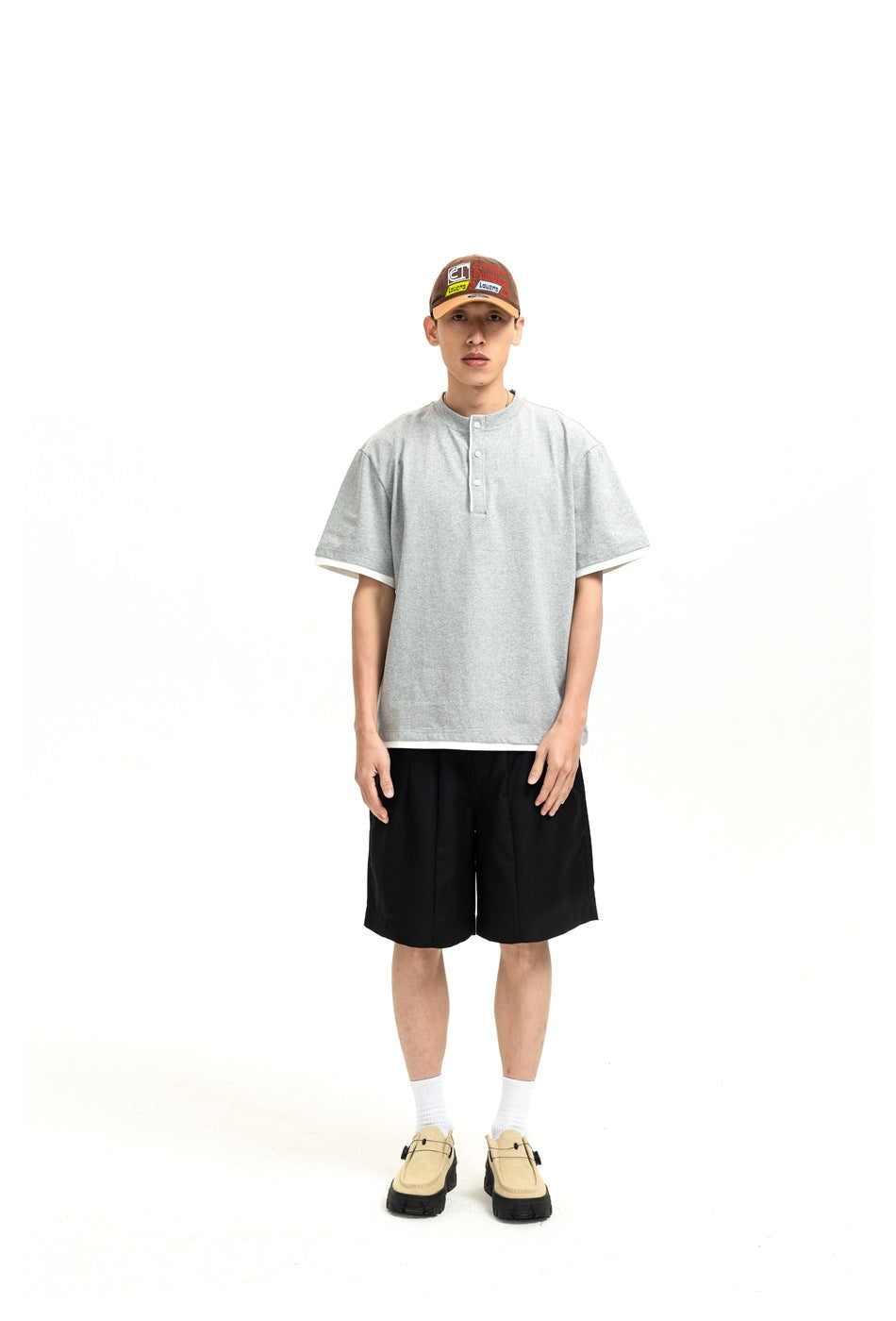Front view of a model wearing black shorts and a light gray short-sleeve henley shirt.