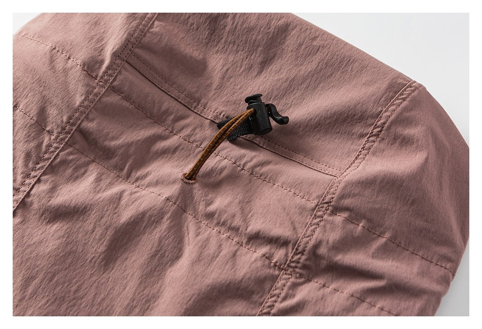 Close-up of a dusty mauve jacket hood with a black cord lock and brown drawcord.