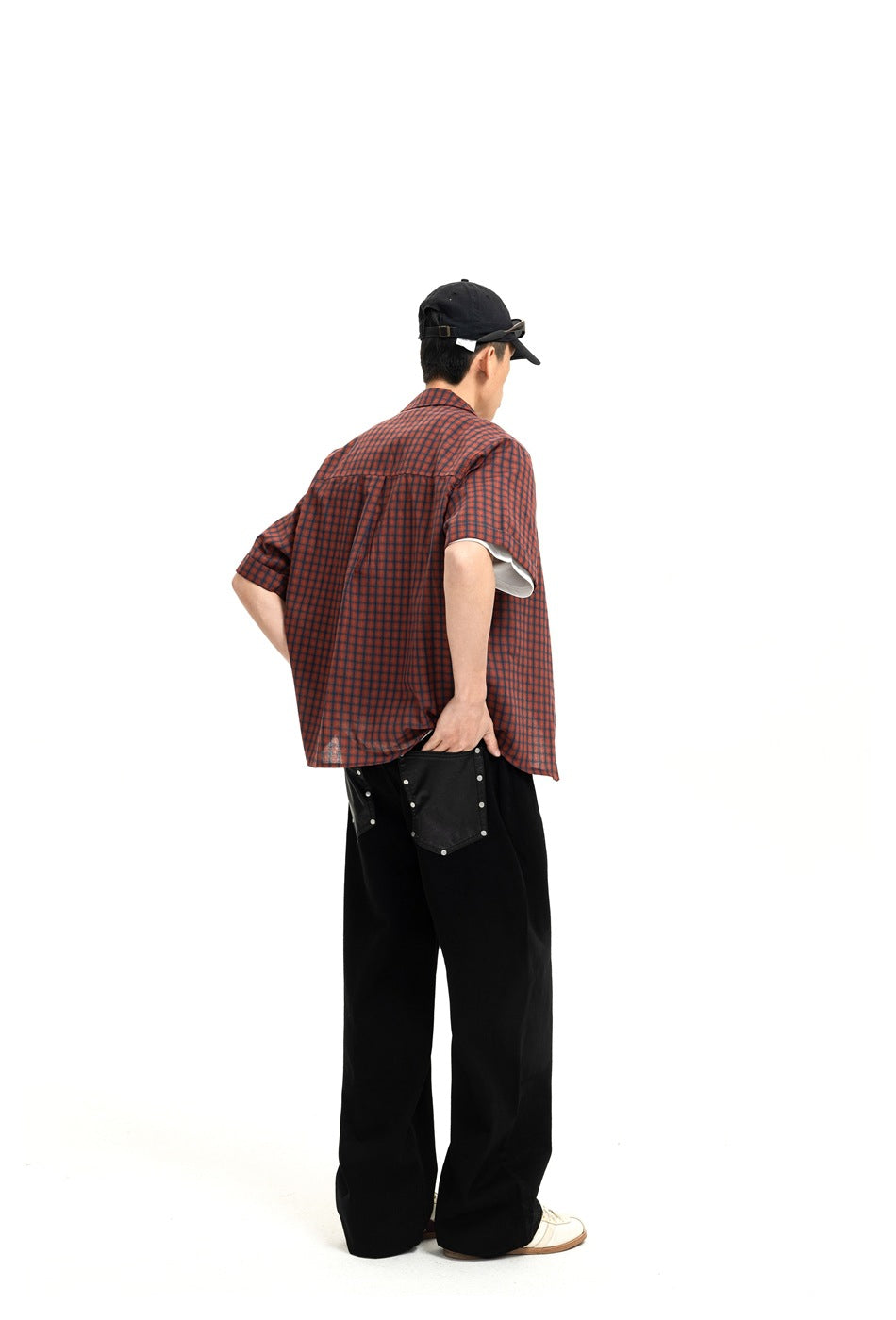 Back view of model in black wide-leg jeans showing dark studded back patch pockets and plaid shirt