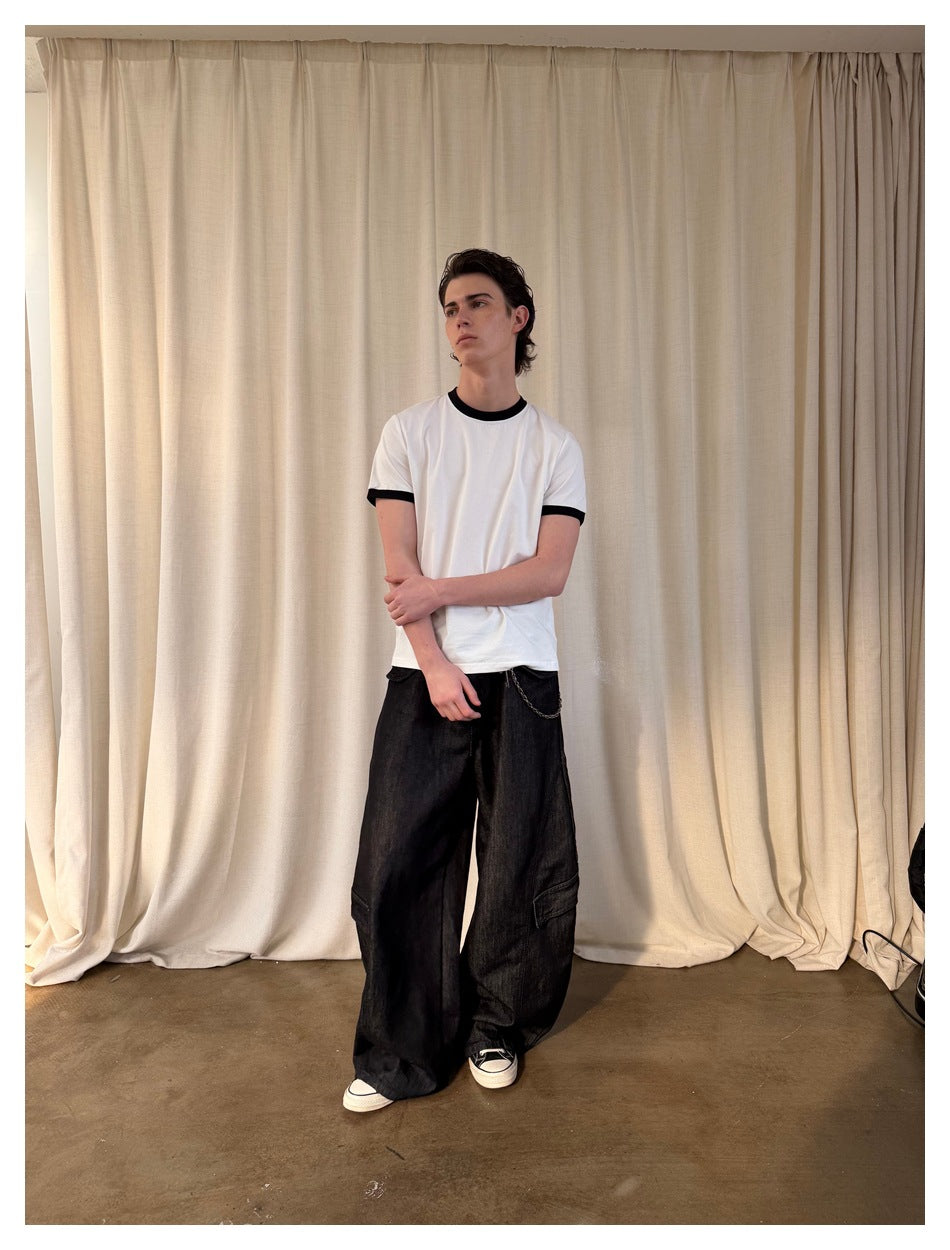 Full-length model wearing a white T-shirt with black trim and wide black pants with cargo pockets.