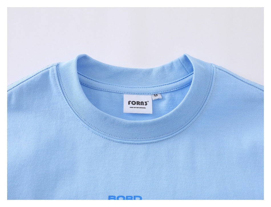 Close-up of a light blue T-shirt's ribbed crew neck, sewn-in label, and partial blue chest print.