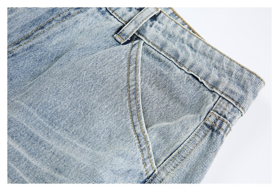 Close-up of a front pocket, belt loop, waistband, and contrast stitching on faded jeans.