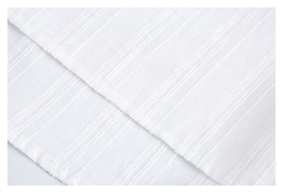 Close-up of white fabric with raised horizontal stripes and a folded stitched edge.