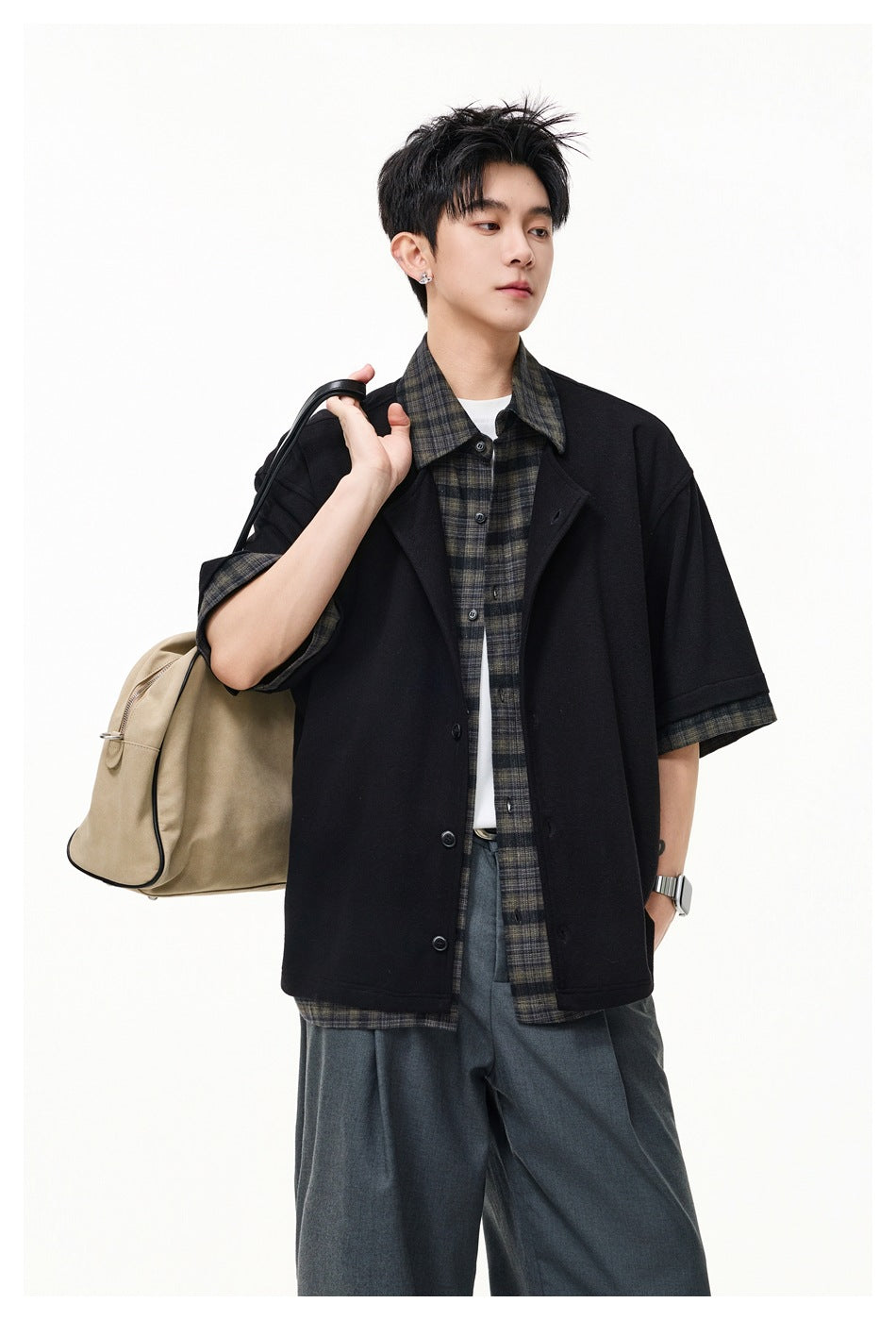 Model wearing a black short-sleeve overshirt with dark plaid collar and cuffs, layered over a matching plaid shirt.