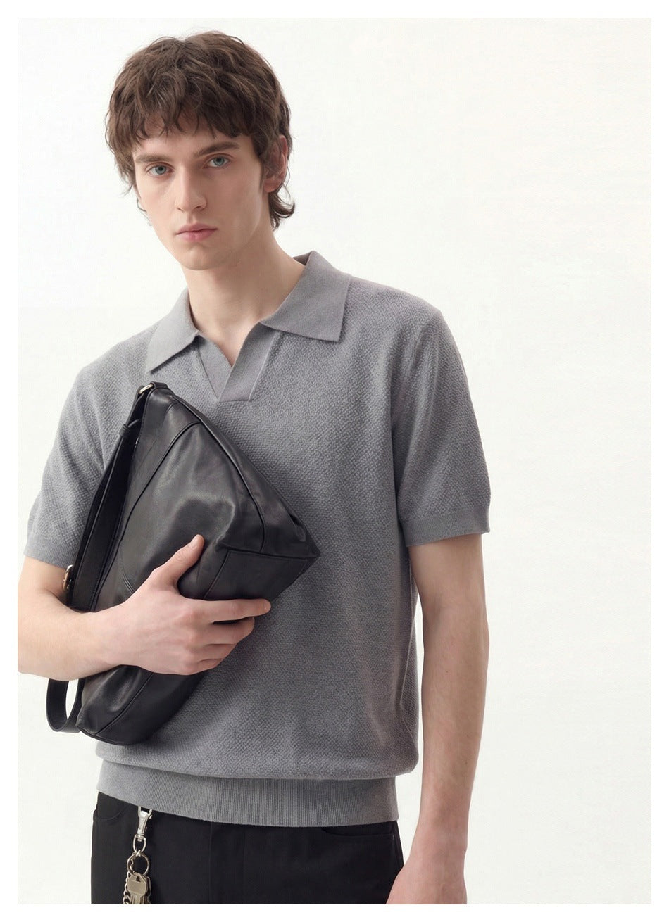 Close view of a model wearing a textured gray short-sleeve polo with a pointed collar and open V neckline.