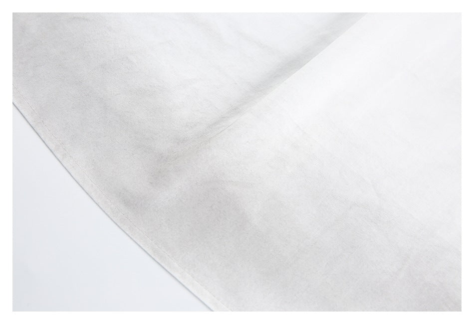 Close-up of a broad white garment panel and its stitched edge.