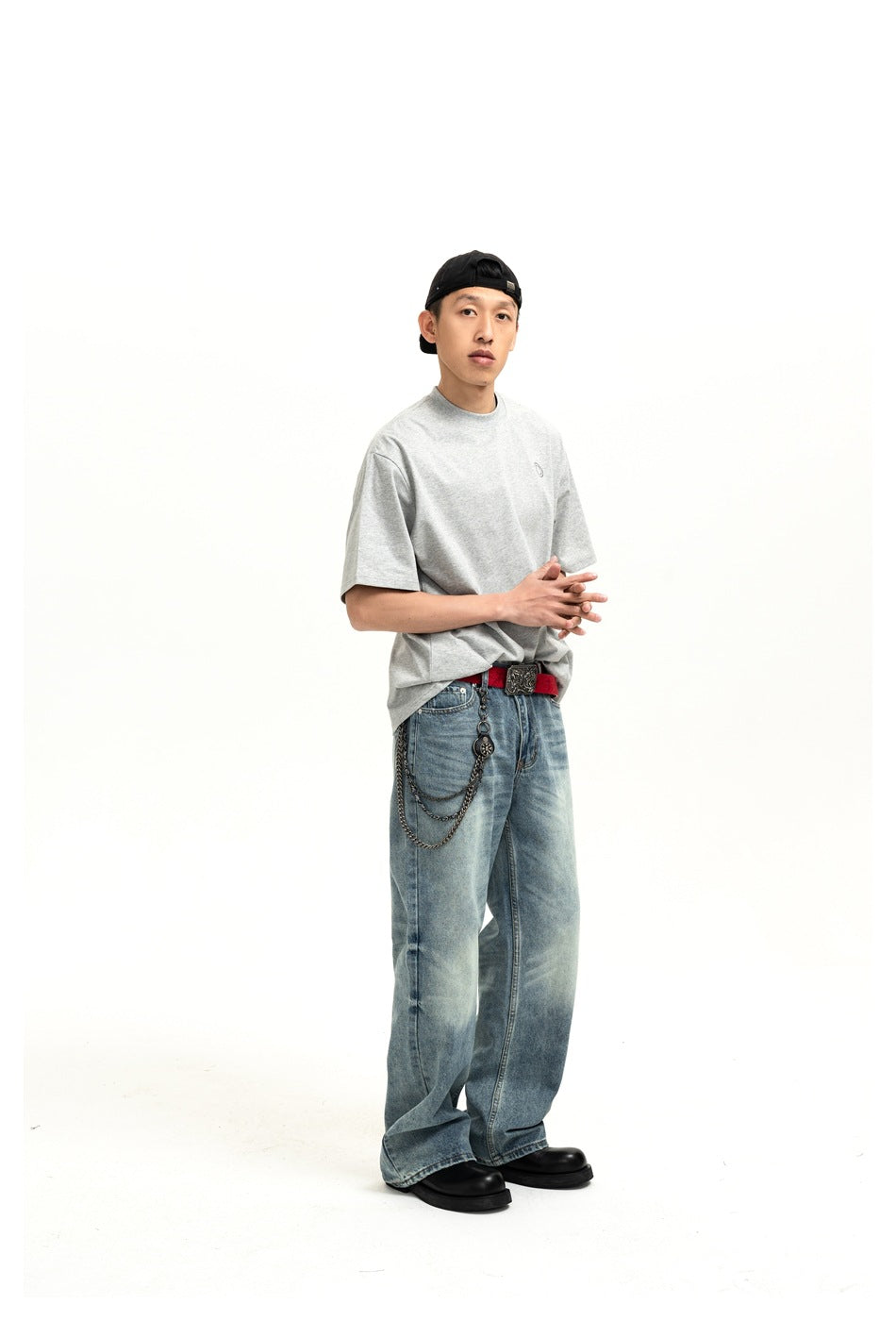 Model in a gray T-shirt, side-angled pose with faded blue jeans, red belt and black boots