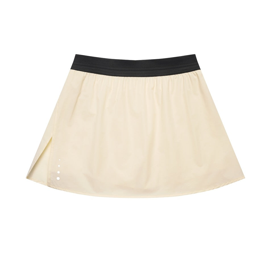 Beige A-line mini skirt with black elastic waistband, side slit and white dots at the hem, flat lay