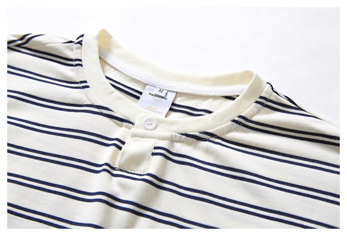 Close-up of an ivory T-shirt with navy stripes, showing the crew neck, button placket, and neck label.