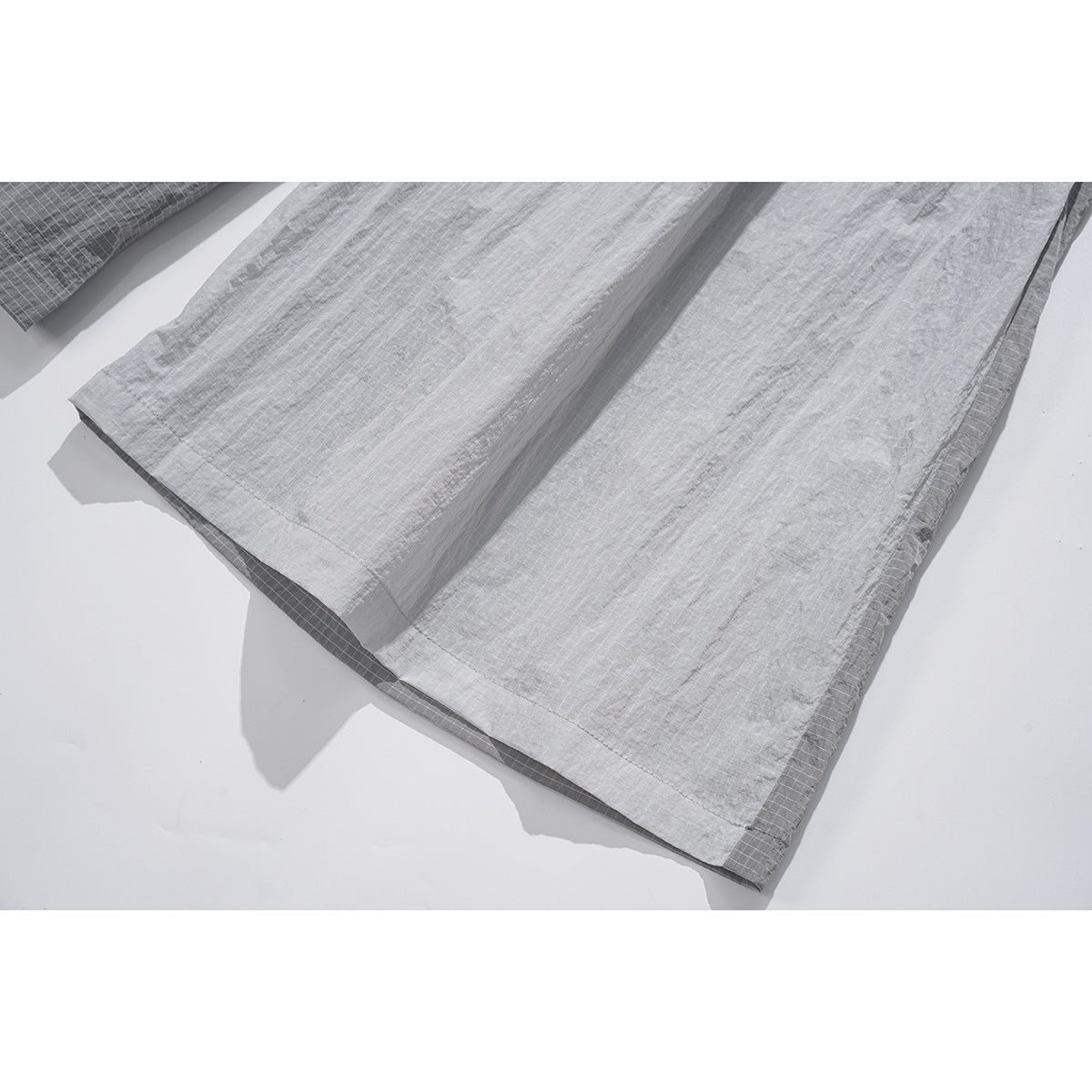 Close-up of the wide gray pant legs and stitched hems, showing the subtle grid pattern.