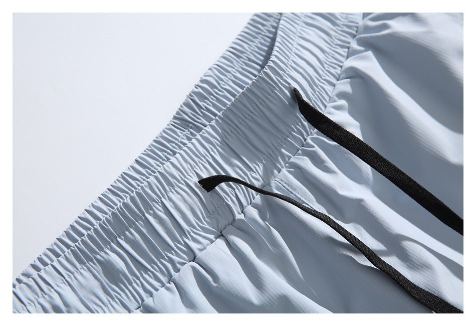 Close-up of the elastic waistband and black drawstrings on pale blue-gray shorts.