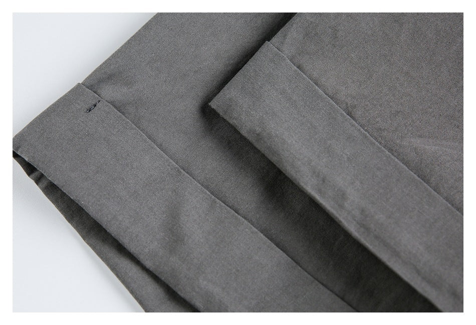 Close-up of a folded charcoal gray cuff with a small buttonhole and layered fabric.