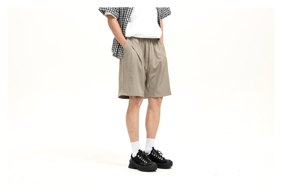 Cropped model wearing light taupe drawstring shorts, shown from the front at a slight angle.