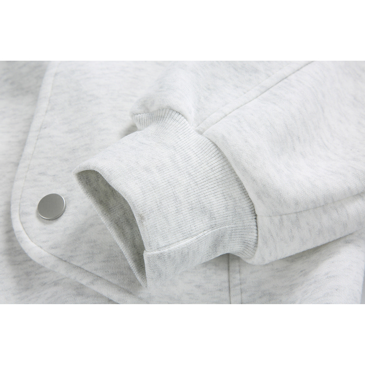 Close-up of the off-white heathered jacket's ribbed cuff and silver snap detail.