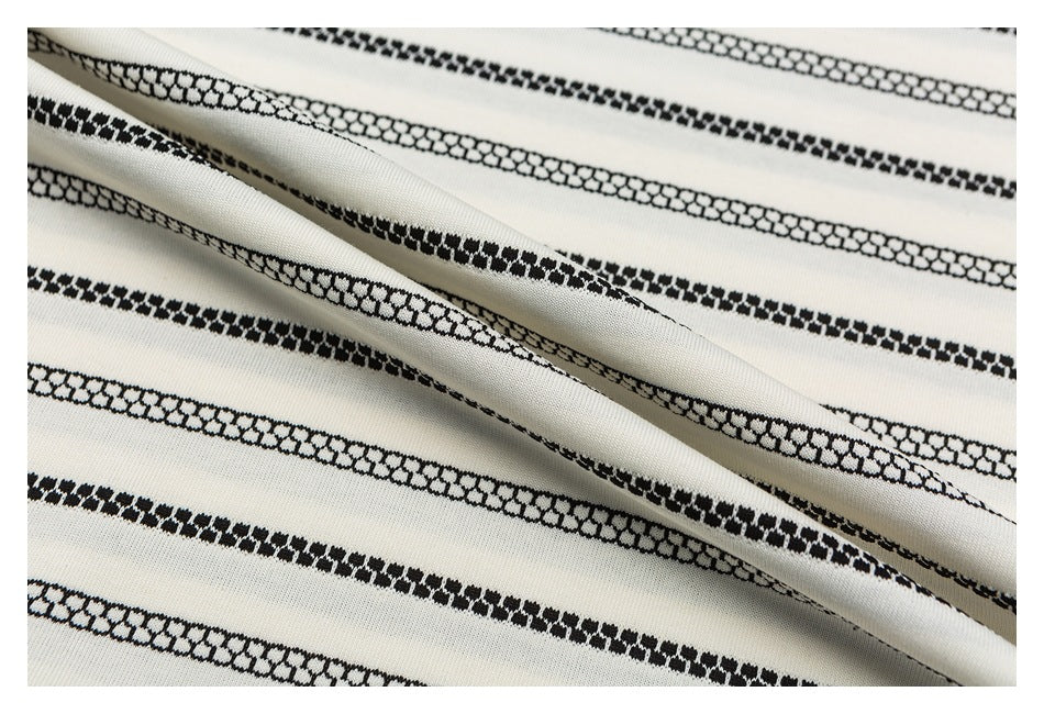 Close-up of draped ivory fabric with repeating black patterned stripes.