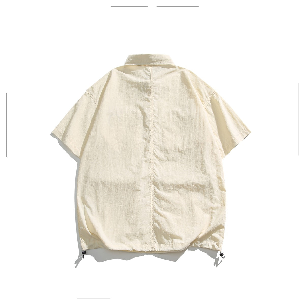 Back view of an ivory oversized short-sleeve collared shirt with a center seam and adjustable hem cords.