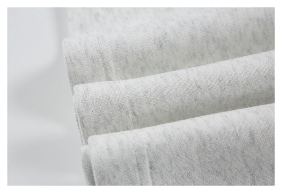Close-up of folded edges and stitching on light gray heathered fabric.
