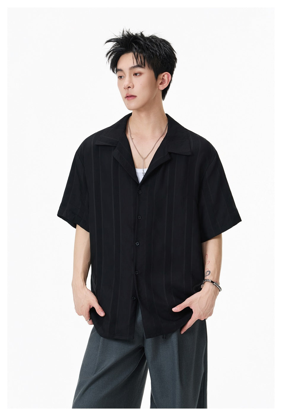 Model wearing a loose black short-sleeve shirt with subtle vertical stripes, shown at a slight angle.