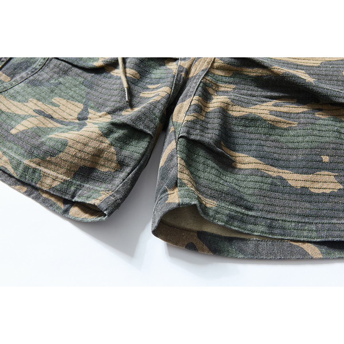Close-up of camouflage shorts showing the hem, layered stitching, and part of a drawstring.