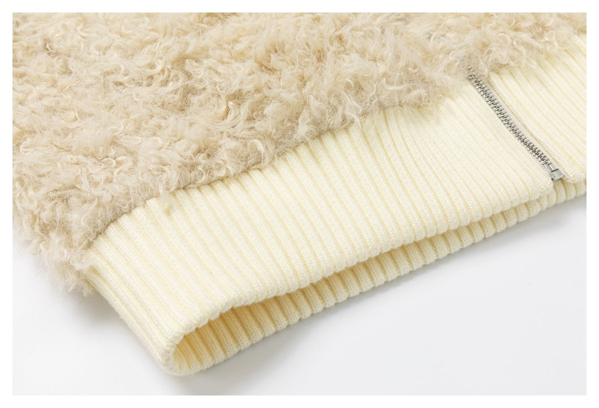 Close-up of a cream curly-fleece jacket with a ribbed hem and silver zipper.