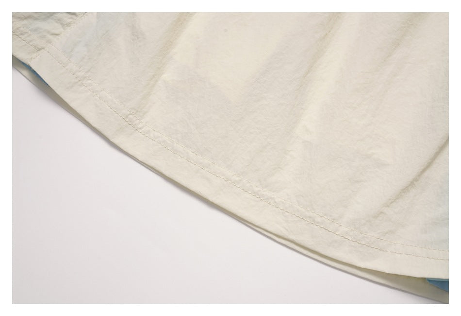 Close-up of the cream skirt’s curved hem and double-row stitching, with a glimpse of blue lining.