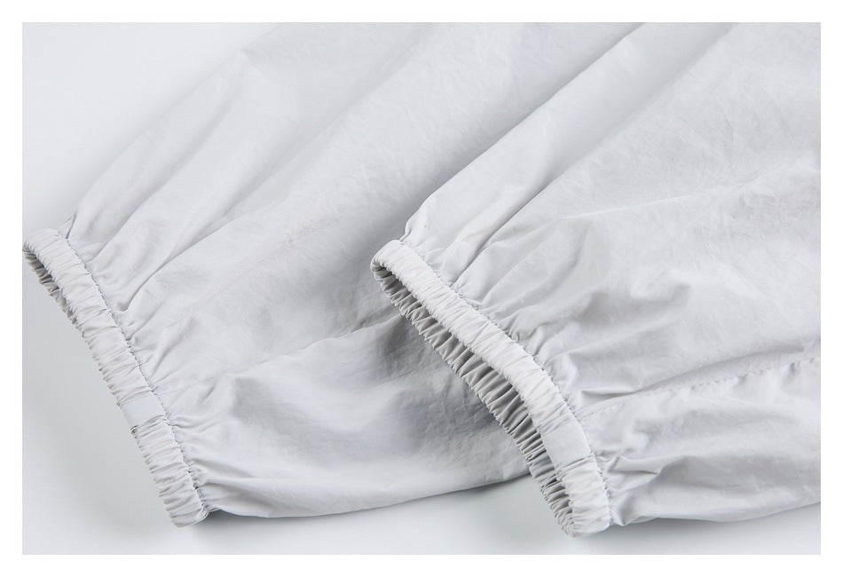 Close-up of two elasticized edges on a light gray garment, showing gathered stitching and softly creased fabric.
