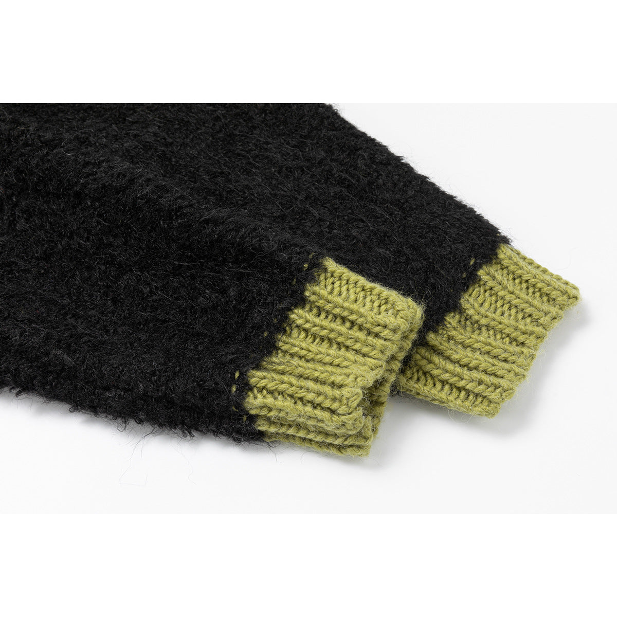 Close-up of a black knit cardigan sleeve with a contrasting olive-green ribbed cuff.