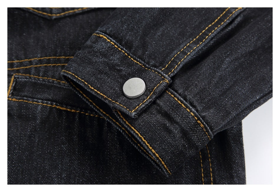 Close-up of a dark denim jacket cuff with a silver snap and gold stitching.