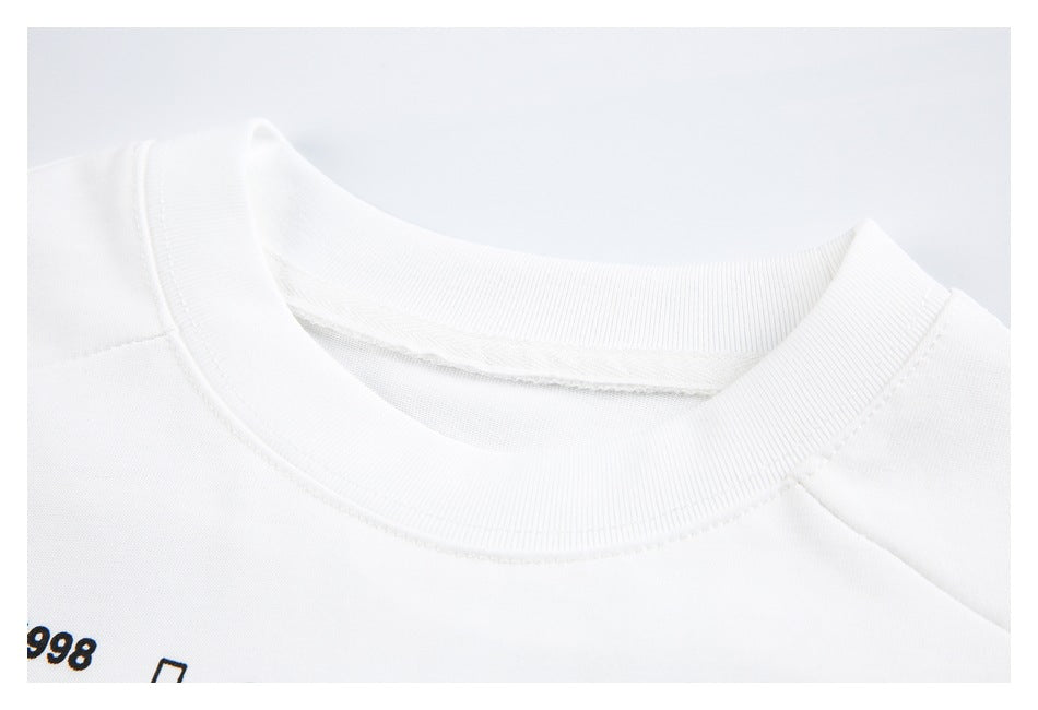 Close-up of the white T-shirt's ribbed crew neckline, shoulder stitching, and partial black chest print.