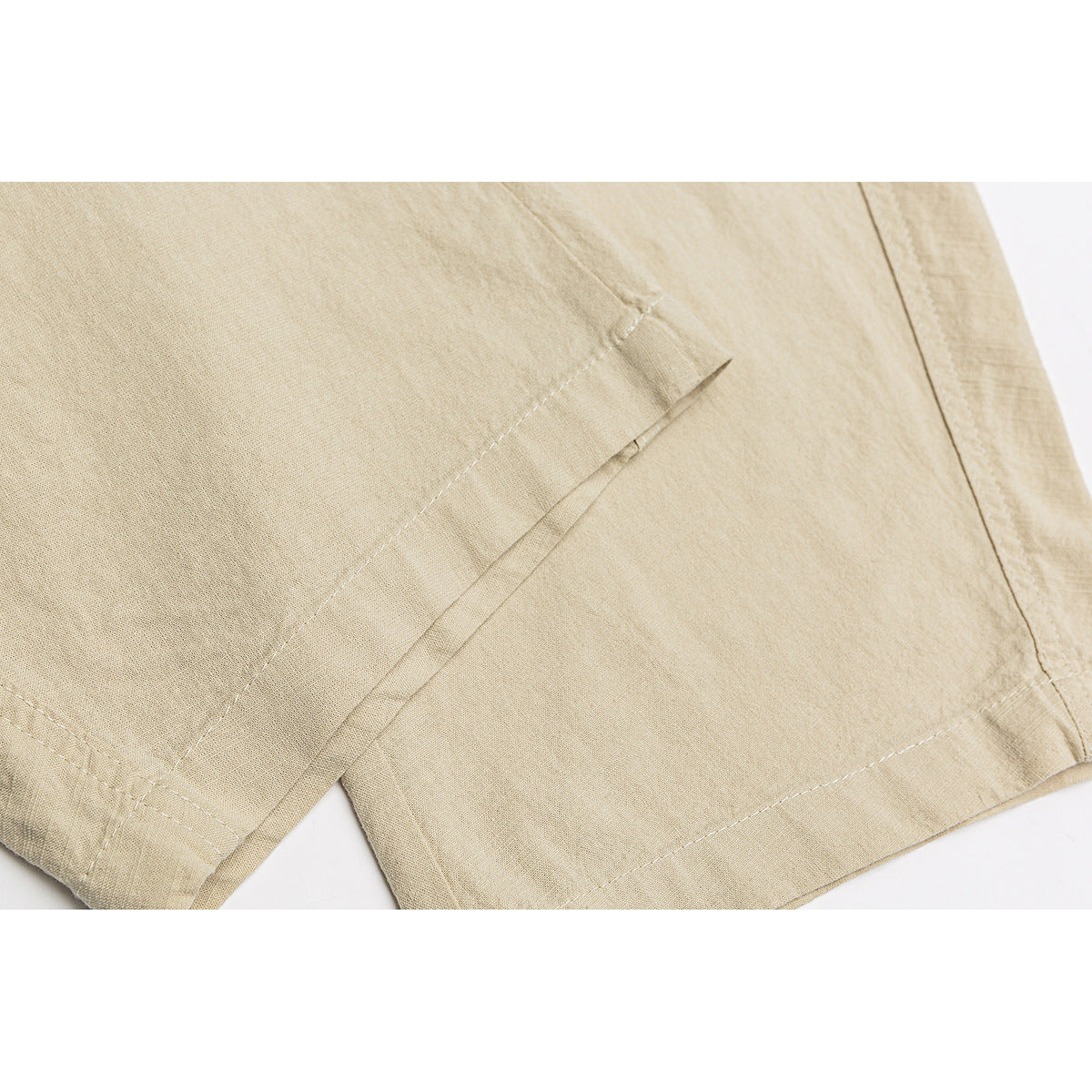 Close-up of beige pants showing a stitched panel seam and finished leg hem.