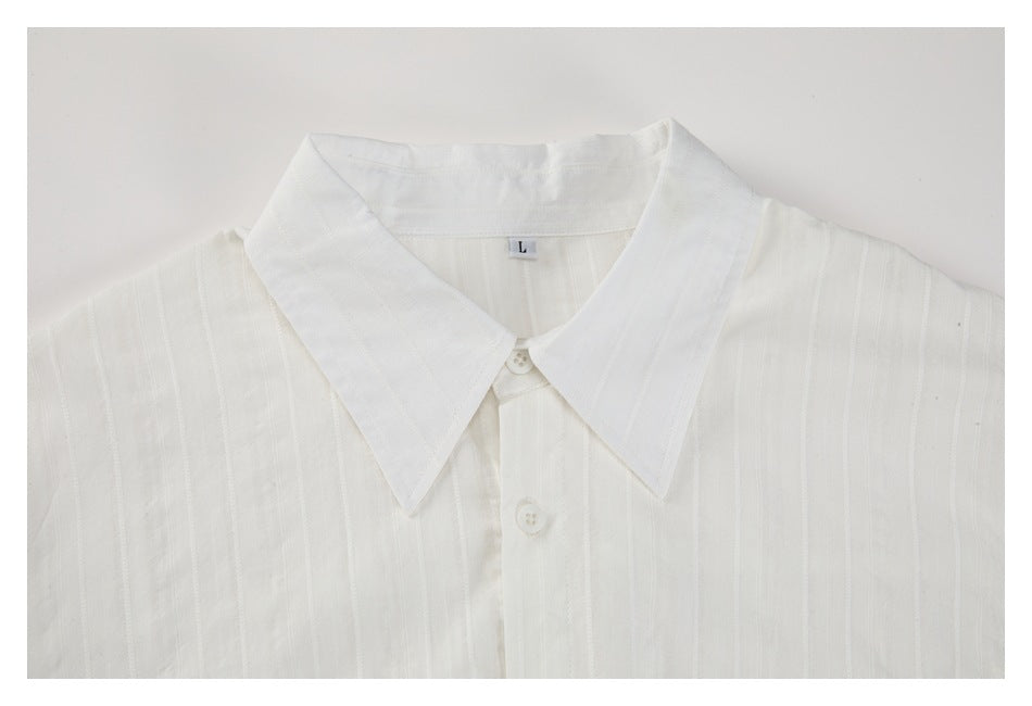 Upper front of a white shirt laid flat, showing its wide pointed collar, buttons, and subtle vertical stripes.