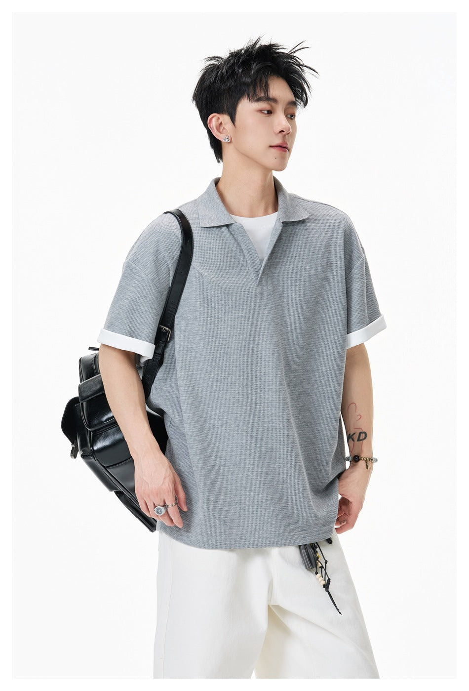 Model wearing a gray textured short-sleeve polo with a collar, open V-neck, and white turned-up cuffs.