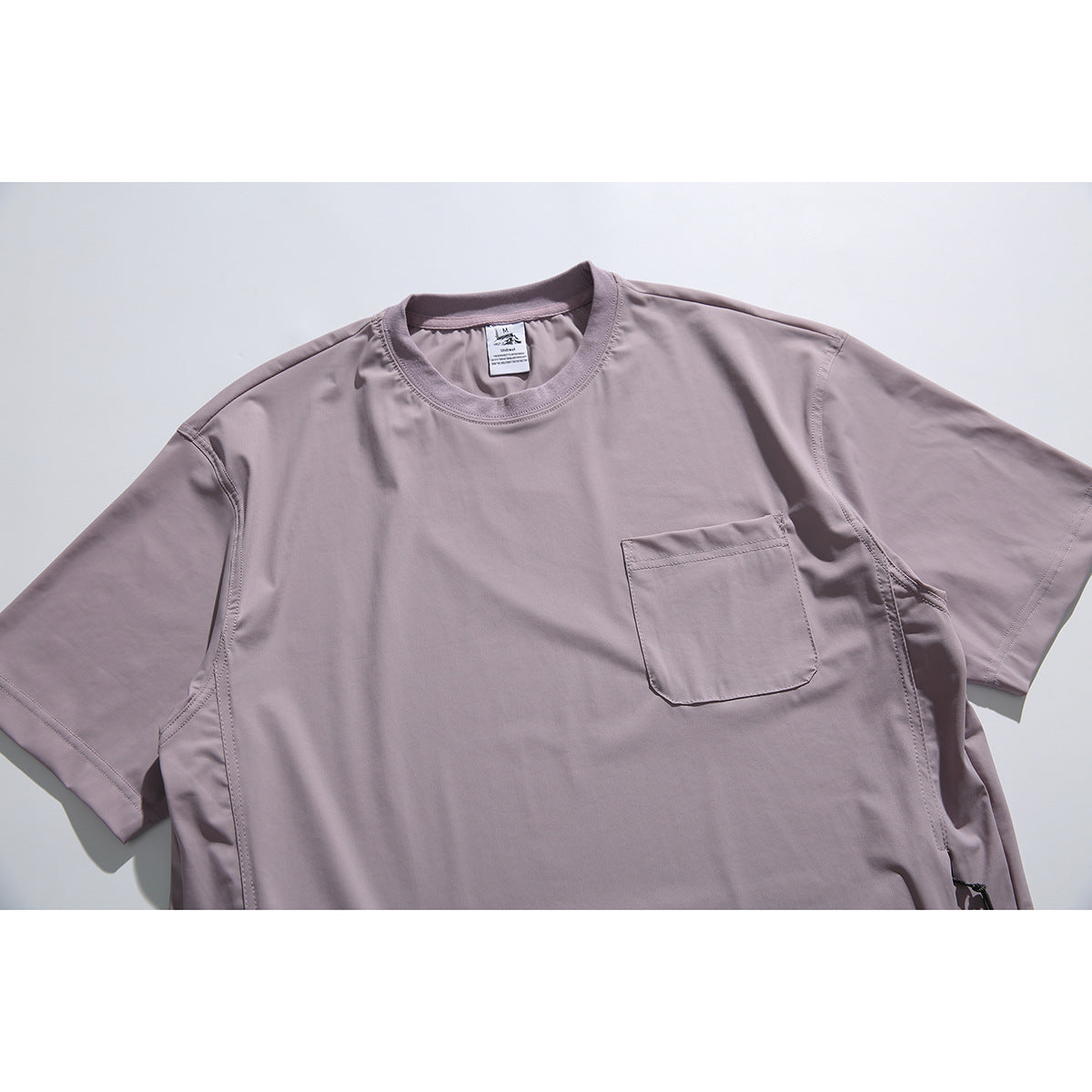 Close view of a dusty mauve short-sleeve crew-neck shirt with a chest pocket and side details.