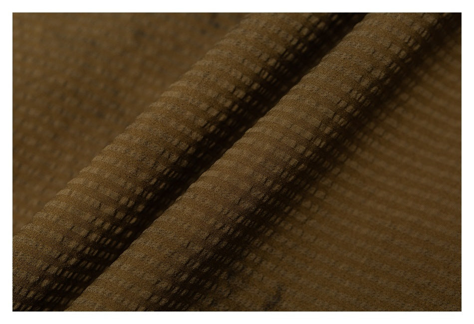 Close-up of brown textured fabric showing a raised folded seam and stitching.