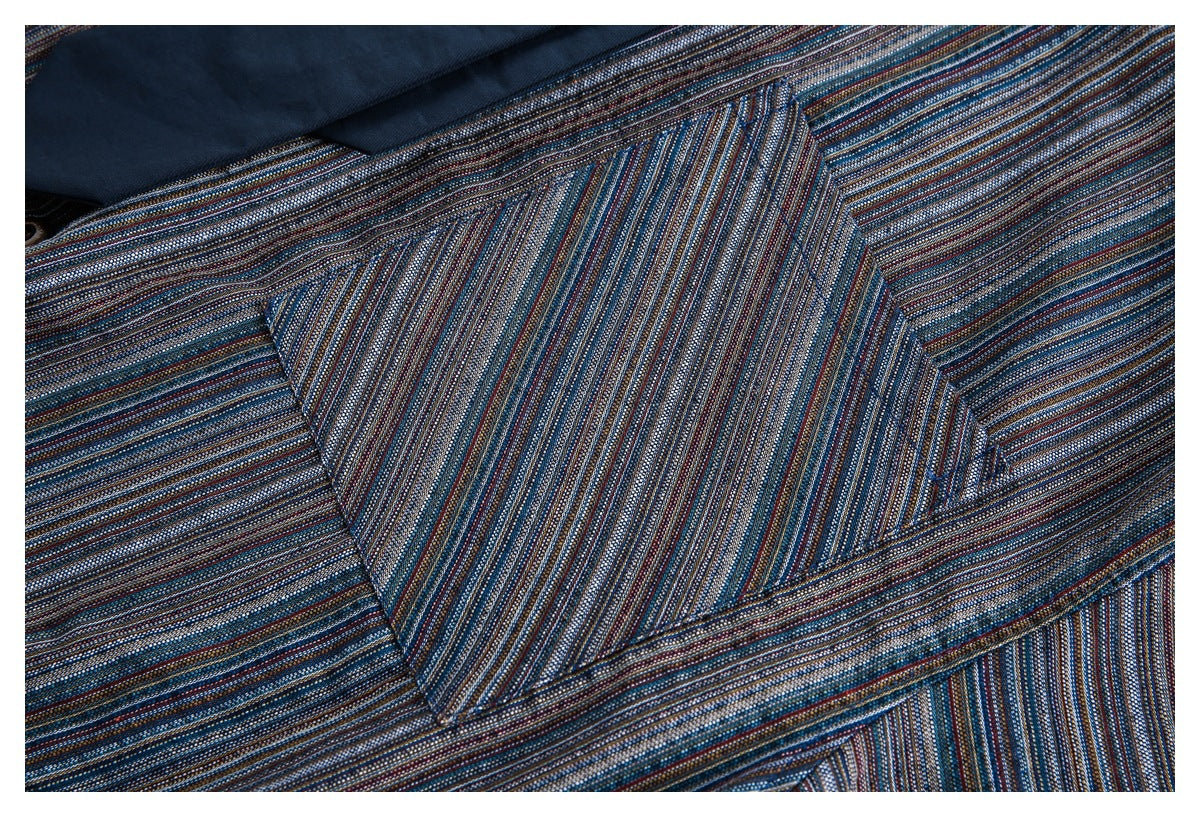 Close-up of a chest pocket on a dark blue shirt with fine multicolor stripes.