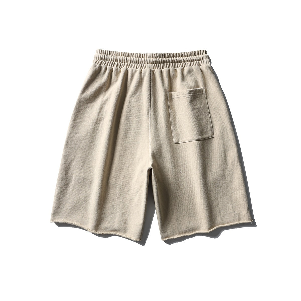 Beige drawstring shorts back view with elastic waistband, patch pocket and raw hem