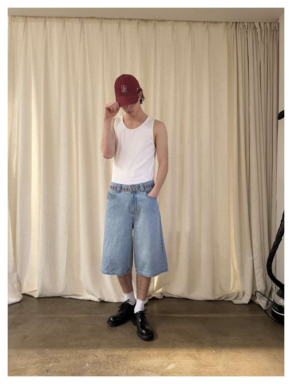 Full-length front view of a model wearing light-wash, wide-leg denim shorts with a patterned waistband.