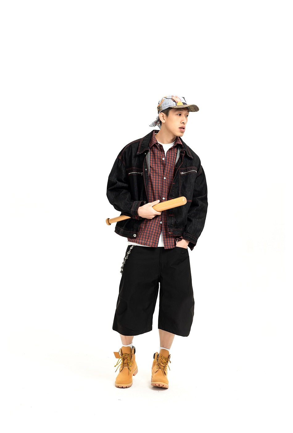 Model wearing a black jacket with red stitching over a red-and-blue plaid shirt, posed against a white background.