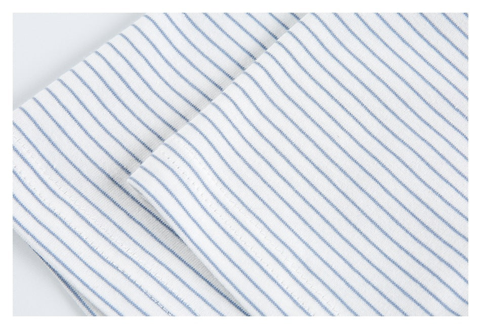 Close-up of a seam and folded edge on white fabric with thin blue stripes.