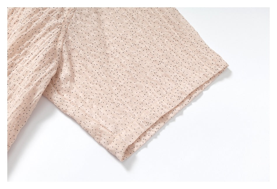 Close-up of the garment's dotted blush hem and overlapping fabric edge.