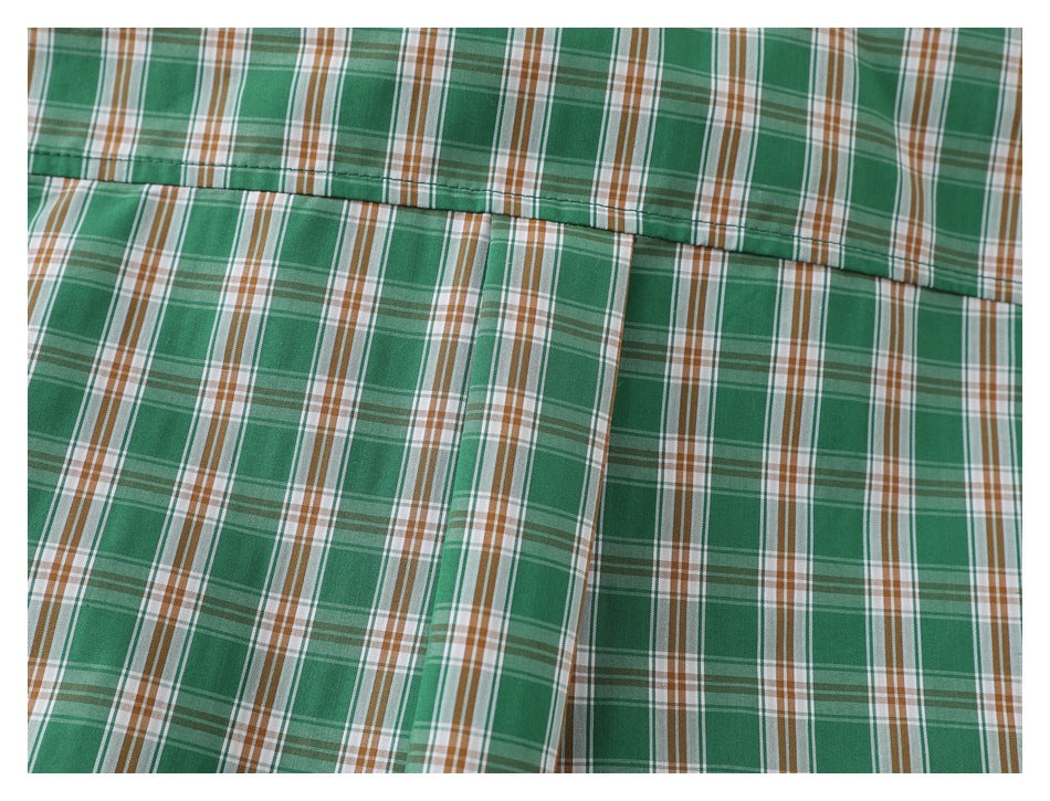 Close-up of a stitched panel seam on the green, white, and brown plaid shirt.