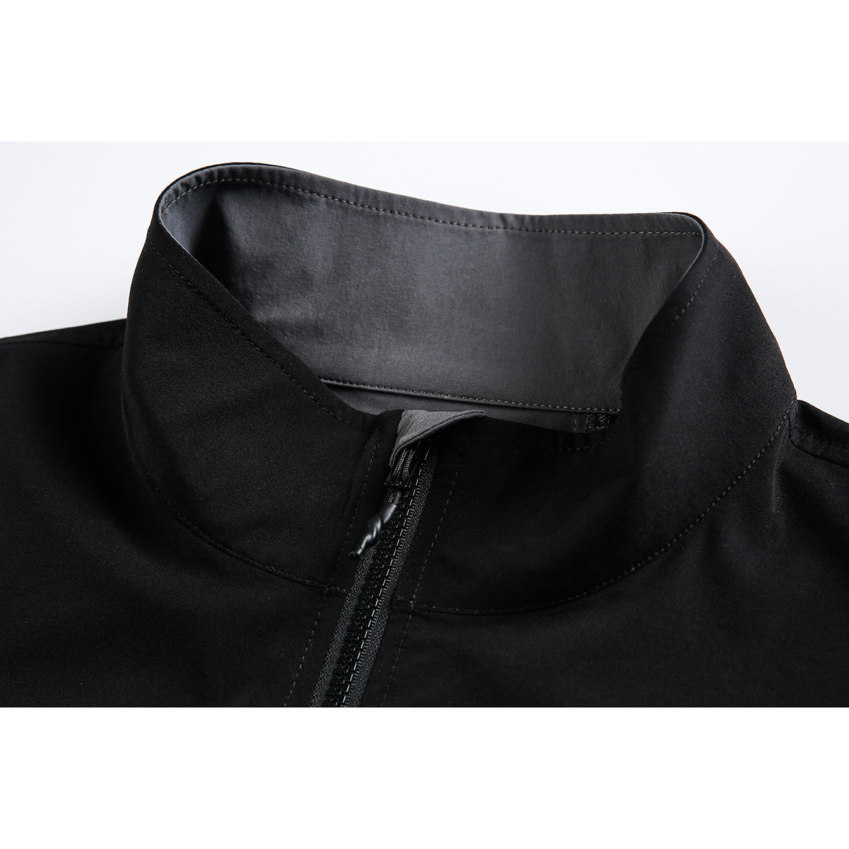Close-up of a black jacket's raised collar, inner facing, and front zipper.