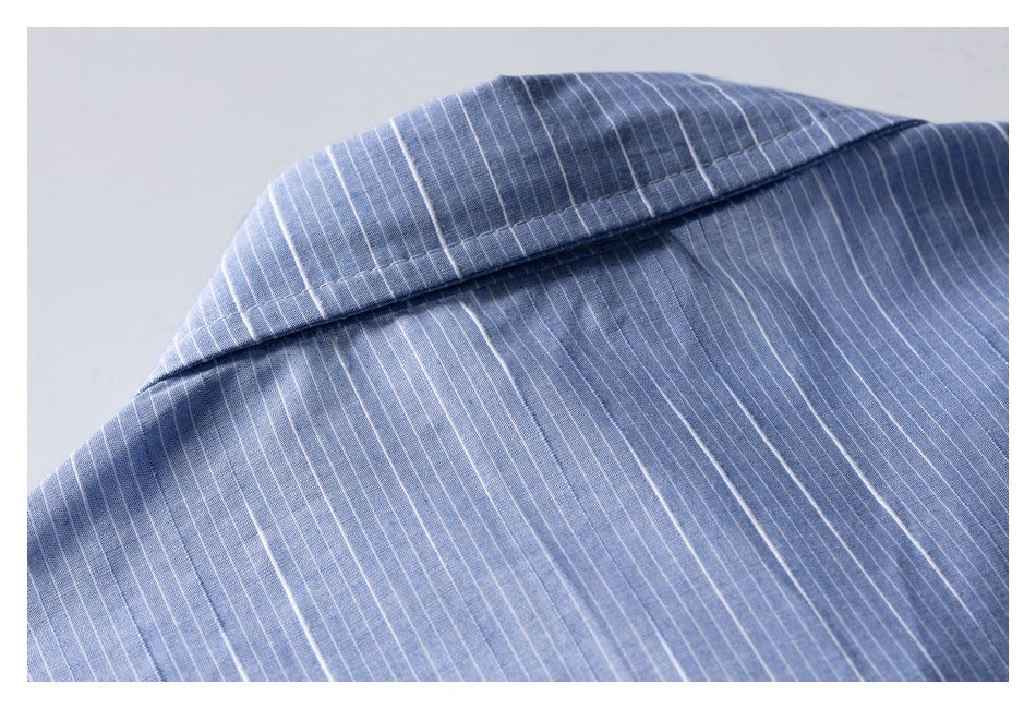 Close-up of a pointed collar on blue fabric with fine white pinstripes.